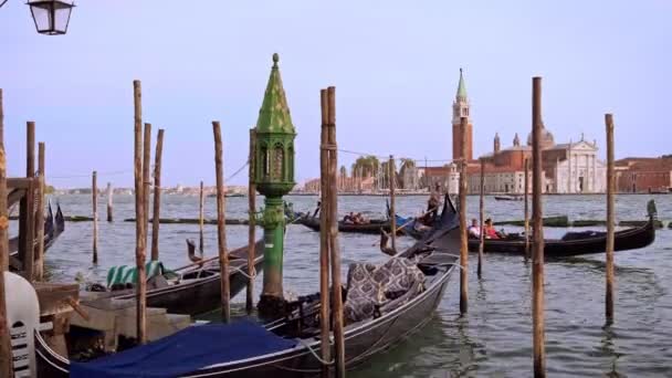 Venedik, İtalya 'daki Büyük Kanal' ın sularında gündüz yüzen Gondollar. San Marco Meydanı yakınlarında mavi örtülü demirli gemiler, turistler gondol yolculuğunun keyfini çıkarıyorlar — Stok video