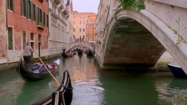 Gondol gün içinde Venedik, İtalya 'da kanala iniyor. Gondolcu dümenci. Turistler gezintiden ve fotoğraf çekmekten hoşlanırlar. Ortaçağ binaları, kanal suları. Venedik