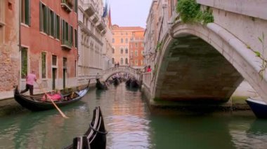 Gondol gün içinde Venedik, İtalya 'da kanala iniyor. Gondolcu dümenci. Turistler gezintiden ve fotoğraf çekmekten hoşlanırlar. Ortaçağ binaları, kanal suları 