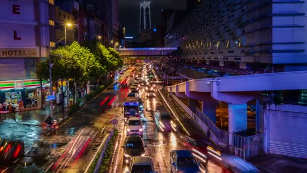 Timelapse nowoczesnej azjatyckiej ulicy miasta w nocy. Ślady świetlne samochodów, światła miejskie, ludzie przecinają ulice, wieżowiec TRX w tle, Kuala Lumpur — Wideo stockowe