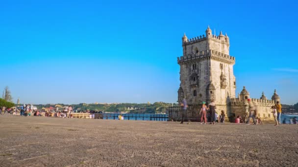 Timelapse 4k: туристы мчатся вокруг знаменитой Белемской башни, Лиссабон, Португалия в солнечный день. Парусные лодки и круизный лайнер на реке Тагус — стоковое видео