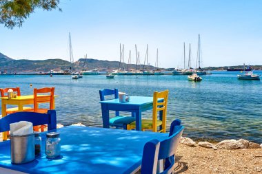 Rum tavernasında gündüz vakti renkli sandalyeler ve masalar. Tatiller, Yunanistan, yaz, restoran, açık hava yemekleri, adalar, liman, marina, yatlar