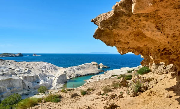 Famous white rocks of Sarakiniko beach, Aegean sea, Milos island , Greece. Empty cliffs, summer day sunshine, clear sea, blue waters, azure lagoon, big orange rock, one adult goes swimming, beautiful