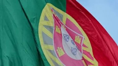 Mavi gökyüzünde güneşli bir günde, soldan sağa esen rüzgarda sallanan Portekiz 'in büyük ulusal bayrağının yakın çekim görüntüsü. Vatanseverlik, demokrasi, siyaset, ulus, Avrupa Birliği üyesi ülke. Gerçek 4k.