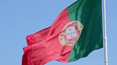 Close view of big national flag of Portugal waving in the wind from right to left on a clear sunny day at blue sky. Patriotism, democracy, politics, nation, European union member country. Selective