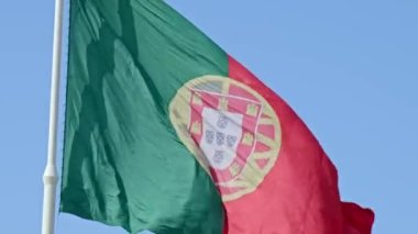 Mavi gökyüzünde güneşli bir günde, soldan sağa esen rüzgarda sallanan Portekiz 'in büyük ulusal bayrağının yakın görüntüsü. Vatanseverlik, demokrasi, siyaset, ulus, Avrupa Birliği üyesi ülke. Seçici