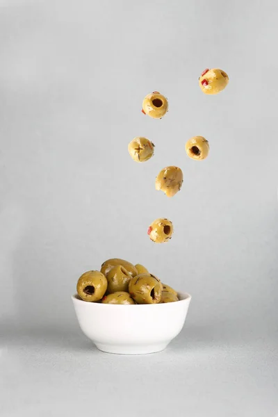 Flying Food Concept Green Olives Pouring White Bowl Gray Background — Stock Photo, Image