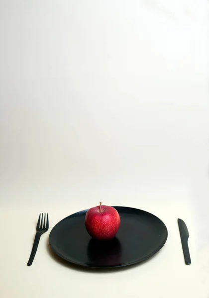 Roter Apfel Auf Schwarzem Teller Mit Schwarzem Plastikmesser Und Gabel — Stockfoto