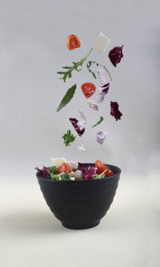 Sağlıklı beslenme konsepti - salata kesesi siyah porselen kaseye hafif arka planda. Resim kopyalama alanı içeriyor