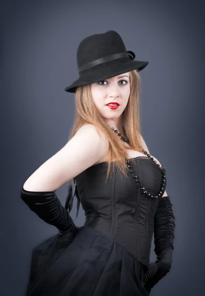 Dívka stojící bokem s černým kloboukem — Stock fotografie