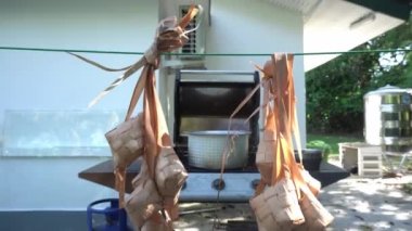Kaynattıktan sonra suyu boşaltmak için ketupat asmak. Ketupat, Endonezya 'da İslami tatiller sırasında özel bir yemektir.