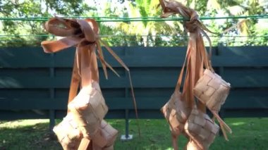 Kaynattıktan sonra suyu boşaltmak için ketupat asmak. Ketupat, Endonezya 'da İslami tatiller sırasında özel bir yemektir.