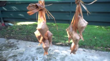 Kaynattıktan sonra suyu boşaltmak için ketupat asmak. Ketupat, Endonezya 'da İslami tatiller sırasında özel bir yemektir.