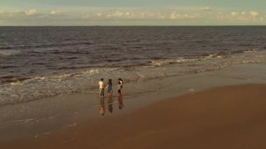 Üç kızı olan büyük Asyalı bir aile tropik sahilde çıplak ayakla oynuyorlar..