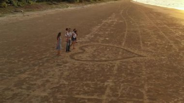 Büyük bir Asyalı ailenin havadan görünüşü kumda kalbi bir araya getirir. Aile, çocukluk ve tatil kavramı.