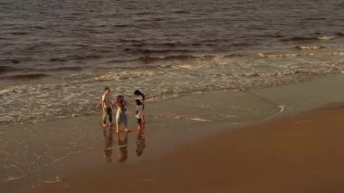 Üç kızı olan büyük Asyalı bir aile tropik sahilde çıplak ayakla oynuyorlar..