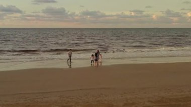 Üç kızı olan büyük Asyalı bir aile tropikal sahilde çıplak ayakla oynuyorlar. Hava görünümü.