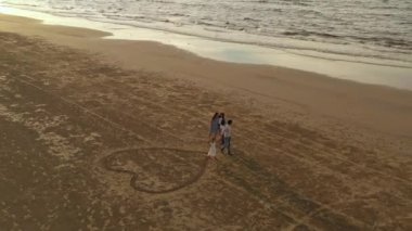 Büyük bir Asyalı ailenin havadan görünüşü kumda kalbi bir araya getirir. Aile, çocukluk ve tatil kavramı.