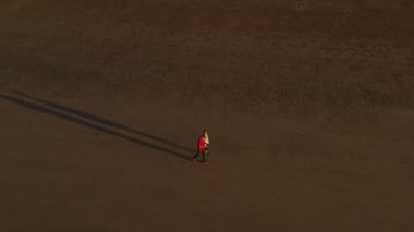 Yukarıdan bakıldığında, tropikal bir plajda yürüyen bir çiftin çarpıcı hava manzarası.