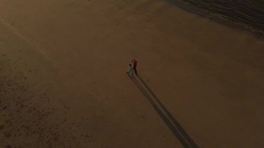 Yukarıdan bakıldığında, tropikal bir plajda yürüyen bir çiftin çarpıcı hava manzarası.