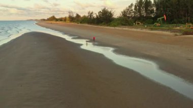 Yukarıdan bakıldığında, tropikal bir plajda yürüyen bir çiftin çarpıcı hava manzarası.