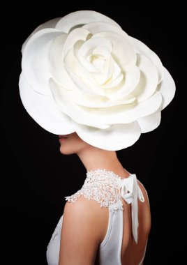 Lüks bir yaşam tarzı, moda ve tarz portresi. Kafasında büyük beyaz bir gül olan zarif bir genç bayan. Siyah arka planda izole edilmiş..