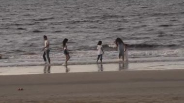 Aile, eğlence ve insanların konsept olarak büyük aileleri tropik plajlarda suda yalınayak koşup oynuyorlar..