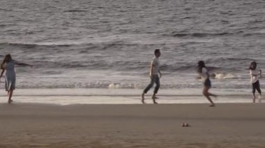 Aile, eğlence ve insanların konsept olarak büyük aileleri tropik plajlarda suda yalınayak koşup oynuyorlar..