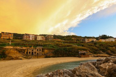 Scenic view of rocky seashore with hotels on background during golden hour