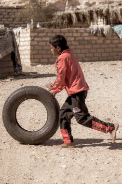 DAHAB, EGYPT - Ocak 2022: Bedevi çocuk Bedevi köyü, Sina, Mısır 'da eski araba lastiğiyle oynuyor