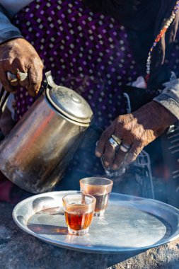 DAHAB, EGYPT - Şubat 2022: Bedevi kadın Mısır 'ın Bedevi köyündeki yangında çay pişiriyor