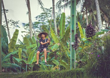BALI, INDONEZYA - Nisan 2022: Balili adam Bali, Endonezya 'da pirinç tarlasında salıncakta