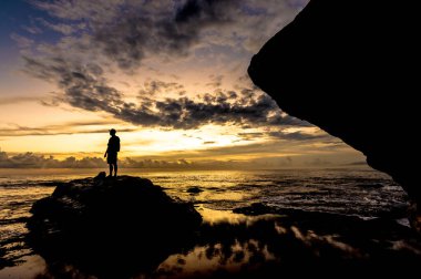 BALI, INDONEZYA - Nisan 2022: Endonezya 'nın Bali kentindeki Tanah Lot tapınağının yakınındaki taşın üzerindeki insan silueti