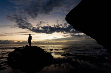 BALI, INDONEZYA - Nisan 2022: Endonezya 'nın Bali kentindeki Tanah Lot tapınağının yakınındaki taşın üzerindeki insan silueti