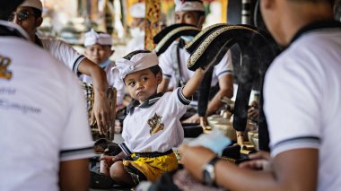 BALI, INDONESIA - April 2022: Cute small Balinese boy wearing traditional costume at traditional ceremony in Balinese temple, Indonesia