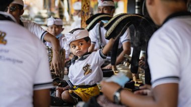 BALI, INDONESIA - April 2022: Cute small Balinese boy wearing traditional costume at traditional ceremony in Balinese temple, Indonesia