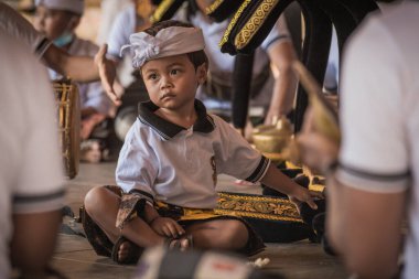 BALI, INDONESIA - April 2022: Cute small Balinese boy wearing traditional costume at traditional ceremony in Balinese temple, Indonesia