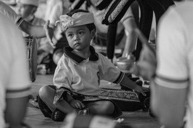 BALI, INDONESIA - April 2022: Cute small Balinese boy wearing traditional costume at traditional ceremony in Balinese temple, Indonesia
