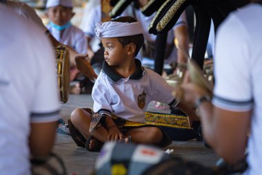 BALI, INDONESIA - April 2022: Cute small Balinese boy wearing traditional costume at traditional ceremony in Balinese temple, Indonesia