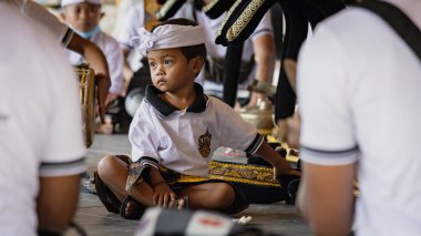 BALI, INDONESIA - April 2022: Cute small Balinese boy wearing traditional costume at traditional ceremony in Balinese temple, Indonesia