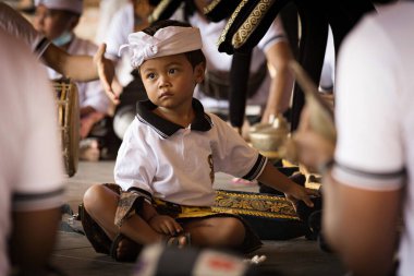 BALI, INDONEZYA - Nisan 2022: Endonezya 'daki Bali tapınağında geleneksel törende geleneksel kostüm giyen sevimli küçük Balili çocuk