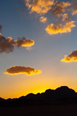 Wadi Rum çölde gün batımı. Turuncu günbatımı gökyüzü ve bulutlar Wadi Rum, Jordan