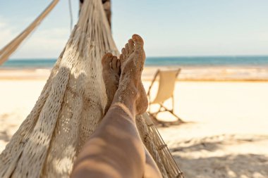 Woman's legs in the hammock against the ocean view