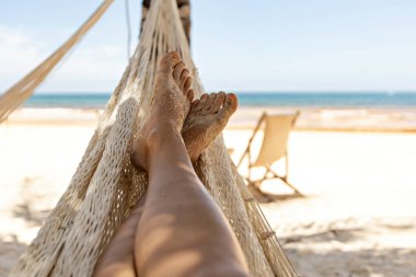 Woman's legs in the hammock against the ocean view