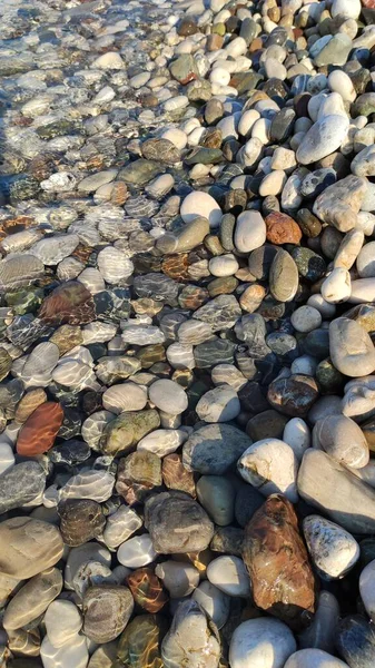 Seaside waves roll over pebbles on beach.