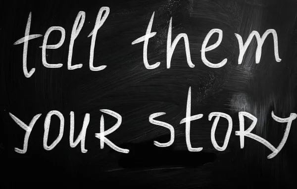 "Tell them your story" handwritten with white chalk on a blackbo — ストック写真