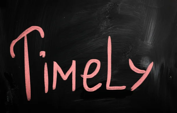 "Timely" handwritten with white chalk on a blackboard — Stock Photo, Image