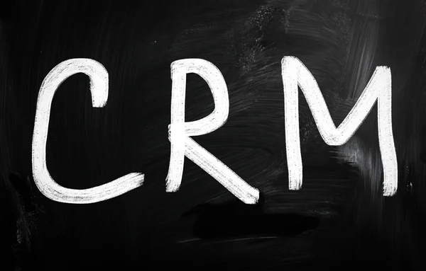 Слово "CRM" написано от руки белым мелом на доске — стоковое фото