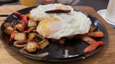 Kahvaltıda kızarmış yumurta, yanında patates ve biber.