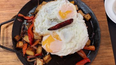 Kahvaltıda kızarmış yumurta, yanında patates ve biber.